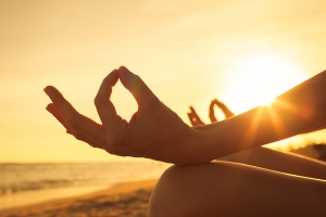 up-close photo of a woman's hands who is meditating on the beach